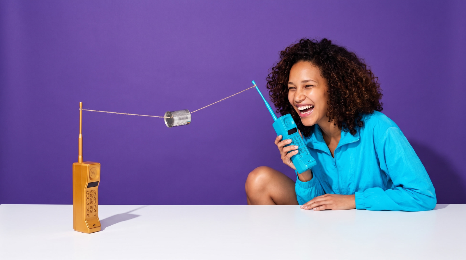 Kai laughing beside two retro walkie-talkies linked by a string-and-tin-can line